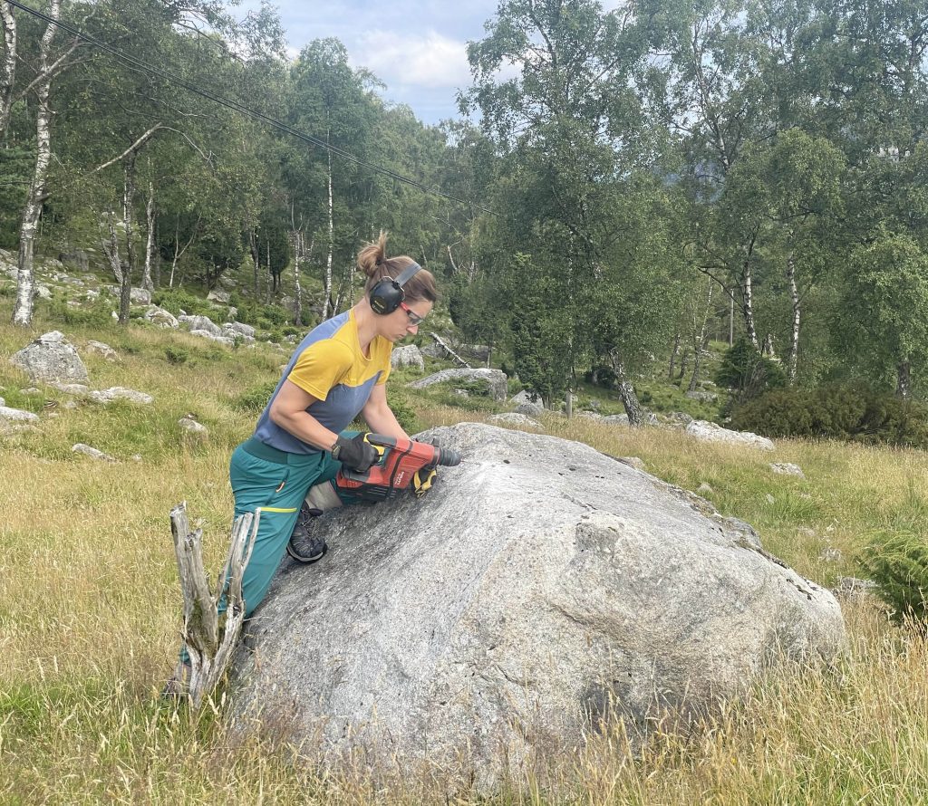 Tricia using a hammer drill to extract a sample.