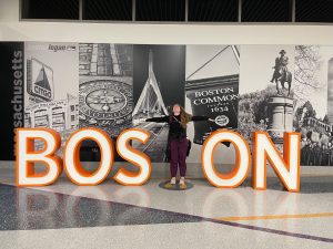 A woman posing with a "Boston" sign