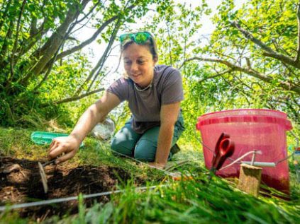 Photo of MacKenzie Anderson excavating in a field location.