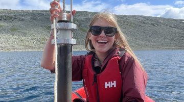 Kayla Guthrie holding soil coring equipment on boat.