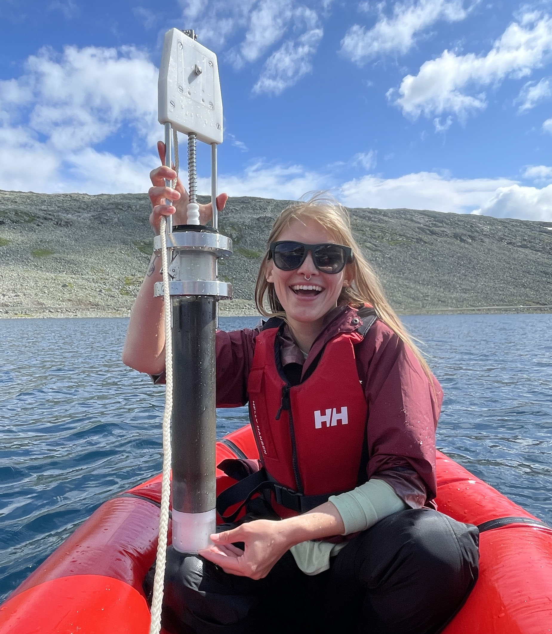 Kayla Guthrie holding soil coring equipment on boat.